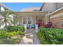 Inviting front porch featuring outdoor seating, lush landscaping, and a brick pathway leading to a striking red front door at 3325 W Wallcraft Ave, Tampa, FL 33611