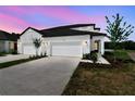 Charming home with a two-car garage, manicured lawn, and a beautifully lit exterior at dusk at 3717 Nandina Cir, Sun City Center, FL 33573