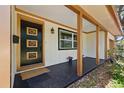 Covered front porch featuring decorative door, black painted concrete and manicured garden at 4926 Camellia S Way, St Petersburg, FL 33705
