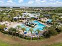 Stunning aerial view of a resort-style pool with a waterslide and lounge chairs, surrounded by lush landscaping at 6337 Shore Vista Pl, Apollo Beach, FL 33572