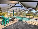 Inviting screened-in pool area featuring a kidney-shaped pool, a brick paver deck, and outdoor seating at 754 Seminole Blvd, Tarpon Springs, FL 34689