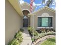 Inviting front door with an arched window detail, flanked by manicured landscaping and a green lawn at 2452 Big Pine Dr, Holiday, FL 34691