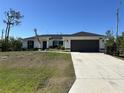 Beautiful home featuring a two-car garage, well-maintained lawn, and an American flag at 12021 Coleman Ave, Port Charlotte, FL 33981