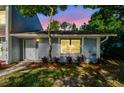 A charming townhome entrance highlighted by lush greenery and colorful landscaping in evening light at 1236 Abbey Crescent Ln, Clearwater, FL 33759