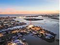 Breathtaking aerial view of a waterfront home with stunning water views and lush landscaping at sunset at 12650 7Th E St, Treasure Island, FL 33706