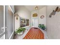 Inviting front entrance featuring a tiled porch, decorative plants, and a glimpse into the bright kitchen through the window at 1613 E Del Webb Blvd, Sun City Center, FL 33573