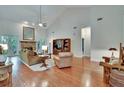Bright living room featuring vaulted ceilings, hardwood floors, a cozy fireplace, and natural light at 16420 Iola Woods Trl, Dade City, FL 33523