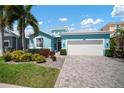 Charming, single-story home features lush landscaping, two-car garage, and a welcoming, light blue exterior at 424 Bahama Grande Blvd, Apollo Beach, FL 33572