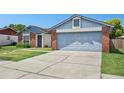 View of the home showcasing a driveway leading to an attached garage with blue trim and brick detailing at 747 Stillview Cir, Brandon, FL 33510