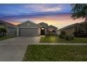 Exterior view of home at sunset, featuring well-kept lawn and landscaping at 13131 Early Run Ln, Riverview, FL 33578