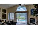 Bright living room with high vaulted ceilings, carpet, fireplace, and sliding glass doors to the outdoor pool at 18412 Oriole St, Lutz, FL 33558
