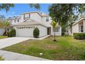 Inviting two-story home featuring a two-car garage, manicured lawn and a young palm tree at 20123 Bay Cedar Ave, Tampa, FL 33647