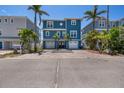 Charming two-story blue home with a double garage and a spacious paved driveway, surrounded by palm trees at 460 137Th Avenue Cir, Madeira Beach, FL 33708