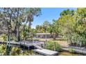 Scenic backyard showcasing a dock leading to the waterway and the rear exterior of the home at 5910 River Rd, New Port Richey, FL 34652