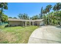 Attractive single story home with manicured lawn, mature palms, a charming entry with arches, and a paved driveway at 5910 River Rd, New Port Richey, FL 34652