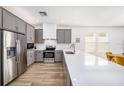 Modern kitchen with gray cabinets, quartz countertops, stainless steel appliances, and wood-look tile flooring at 672 Old Windsor Way, Spring Hill, FL 34609