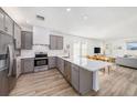Well-lit kitchen featuring stainless steel appliances, gray cabinetry, quartz countertops, and wood floors at 672 Old Windsor Way, Spring Hill, FL 34609