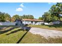 Single-story home with a gravel driveway, fenced yard, and a mix of trees and greenery at 6907 W Creek Dr, Tampa, FL 33615