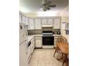 Functional kitchen with white cabinetry, appliances, and a small table, offering a practical space for meal preparation at 7645 Sun Island S Dr # 306, South Pasadena, FL 33707