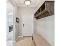 Bright entryway featuring a coat rack with bench, tile floors, and modern lighting fixtures at 8227 Bird Whistle Ln, Land O Lakes, FL 34637