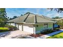 Side view of home featuring a spacious three car garage, mature shrubbery and manicured lawn at 9159 Highland Ridge Way, Tampa, FL 33647