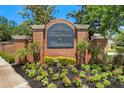 Elegant brick community entrance sign featuring 'Traditions at Woodmont' amidst lush landscaping and colorful flowerbeds at 13312 Tiger Lilly Ln, Tampa, FL 33625