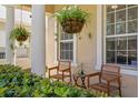 Cozy front porch with hanging plants, wooden chairs, and manicured shrubs with white trim window at 13312 Tiger Lilly Ln, Tampa, FL 33625