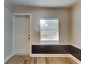 Bright room with wood-look floors, a window with blinds, and a white door at 1361 Overlea St, Clearwater, FL 33755