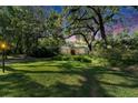Lush front lawn and mature trees surround this charming home with a red door at 1603 Cottagewood Dr, Brandon, FL 33510