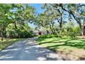 Long driveway leads to a charming home surrounded by mature trees and lush lawn at 1603 Cottagewood Dr, Brandon, FL 33510