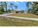Well-maintained single-story home with a long drive, complemented by lush, green landscaping and beautiful trees at 4344 Eldron Ave, North Port, FL 34286
