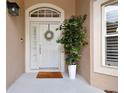 Welcoming front door with a welcome mat, wreath, sidelight, and large potted plant at 6006 Chellas Ct, Lutz, FL 33558