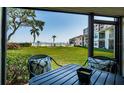 View from the screened patio of a green lawn, trees, buildings, and the beach in the distance at 6265 Sun Blvd # 115, St Petersburg, FL 33715