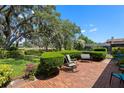 Relaxing brick patio shaded by a large tree and lush landscaping, perfect for outdoor living at 12904 Teakwood Ln, Hudson, FL 34667