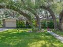 Inviting home with well-manicured lawn, mature trees, and charming stone accents and attached garage at 14350 11Th St, Dade City, FL 33523