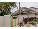 Inviting home entrance featuring a colorful gate, lush landscaping, and a charming facade at 2800 Gulf Blvd Unit # 1A, Belleair Beach, FL 33786