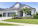 Beautiful home exterior showcasing a well-manicured lawn, lush landscaping, and a three-car garage at 324 3Rd N Ave, Safety Harbor, FL 34695