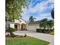 Charming home with a manicured lawn, palm trees, and a paver driveway leading to an attached two-car garage at 522 Planters Manor Way, Bradenton, FL 34212