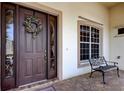 Inviting front entryway featuring a classic door, decorative wreath, and an elegant bench at 522 Planters Manor Way, Bradenton, FL 34212