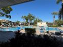 Inviting community pool with lounge chairs, lush landscaping, and clear blue skies perfect for relaxing and enjoying the Florida sunshine at 5980 80Th St N # 106, St Petersburg, FL 33709