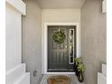 Close-up of a charming front door with a welcoming wreath, sidelight window, and stylish welcome mat at 6910 Rock Springs Way, Tampa, FL 33625
