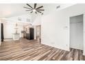 Open-concept living area featuring wood flooring, vaulted ceilings, and a seamless flow to the kitchen at 7309 N Huntley Ave, Tampa, FL 33604
