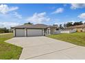 Well-designed home with a long concrete driveway leading to a three-car garage and pristine lawn at 7372 Madrid Rd, Weeki Wachee, FL 34613