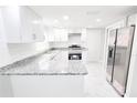 Bright kitchen with stainless steel appliances, granite countertops, subway tile backsplash, and ample cabinet space at 7740 Sagebrush Dr, Port Richey, FL 34668