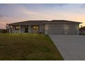 Charming single-story home with a well-manicured lawn and a spacious two-car garage at sunset at 10493 Grail Ave, Englewood, FL 34224