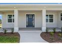 Welcoming front porch with elegant columns and a stylish front door with glass accents, enhanced by new landscaping at 10493 Grail Ave, Englewood, FL 34224