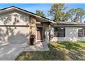 Traditional home featuring a stone facade, a front lawn, and a dark-colored front door at 15118 Brushwood Dr, Tampa, FL 33624