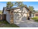 Attached two-car garage with stone accents and a well-maintained lawn at 15118 Brushwood Dr, Tampa, FL 33624
