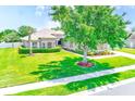 Beautiful single-Gathering home boasts a lush green lawn, mature tree, and manicured landscaping at 2250 Mountain Ash Way, New Port Richey, FL 34655