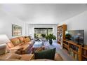 Bright living room featuring a plush leather sofa, large windows with sheer curtains, and built-in bookshelves at 2900 Cove Cay Dr # 1B, Clearwater, FL 33760